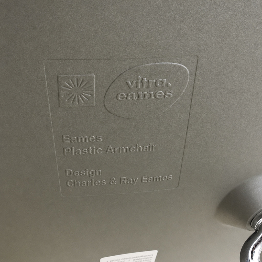 Prägung auf der grauen Sitzschale eines Vitra Eames Plastic Armchair DAR mit Chromgestell.
